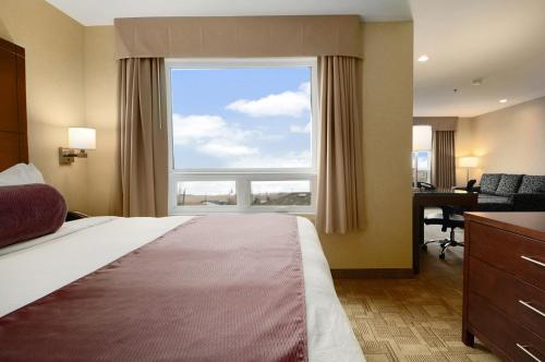 a bedroom with a bed with a large window and a desk at Days Inn by Wyndham Regina Airport West in Regina