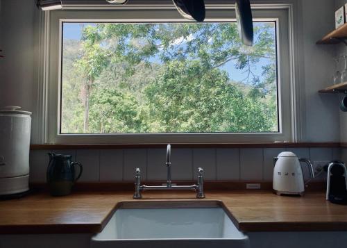 um lavatório de cozinha com uma grande janela por cima em The Pottery Shed em Boambee