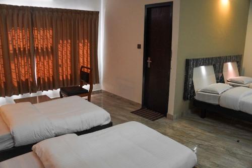 a hotel room with two beds and a window at Hotel Prasanth in Ernakulam