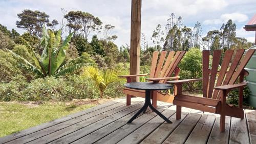 2 chaises et une table sur une terrasse en bois dans l'établissement The Hideout, à Mangawhai
