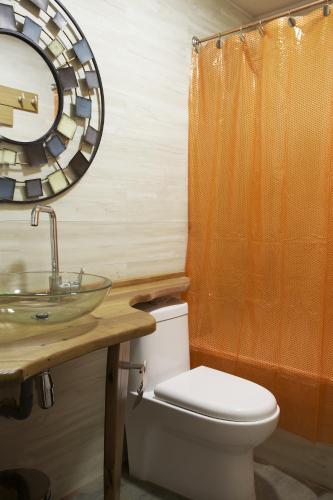 a bathroom with a toilet and a sink and a mirror at Apart Hotel Bianco in El Colorado