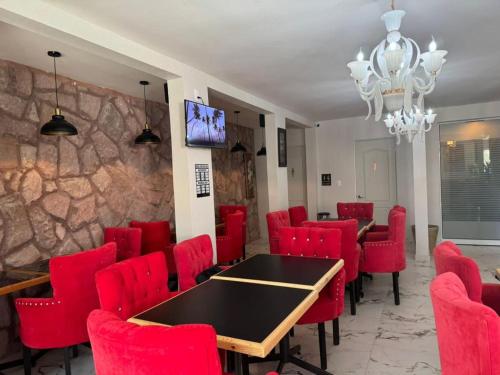 a conference room with red chairs and a table and a wall at Royal Madero Inn Express in Tampico