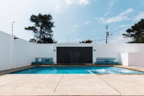 una piscina junto a una pared blanca con chimenea en Pacoa a una cuadra de la playa y vista al mar, en San Pablo