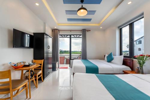 a hotel room with two beds and a table and a desk at Rockmouse Centre River Villa Hoi An in Hoi An