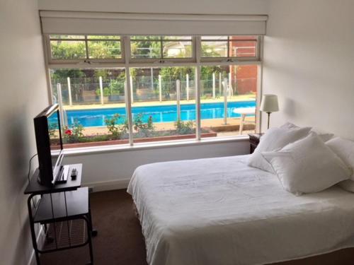 a bedroom with a bed and a large window at Millswood Apartment in Unley