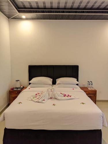 a bed with white sheets and flowers on it at Pohon Purba Resort & Restaurant in Labuan Lombok