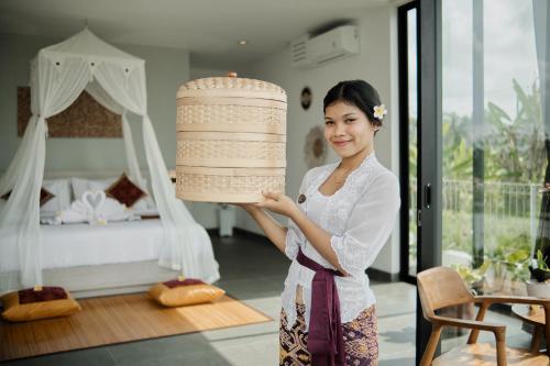 a woman holding a large cake in a bedroom at Van Sheva Ubud Villa in Ubud
