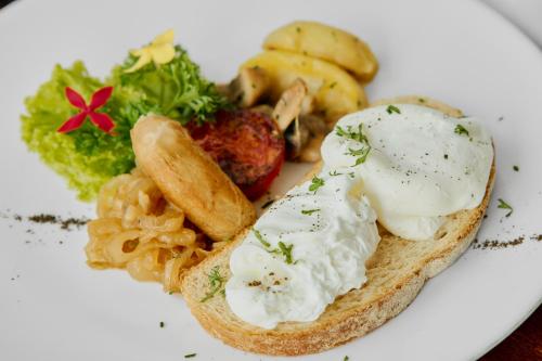 a white plate with a piece of bread with eggs and vegetables at Van Sheva Ubud Villa in Ubud