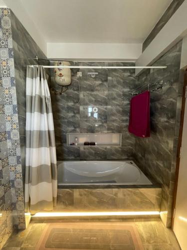 a bathroom with a tub and a shower curtain at The Retreat in Jhunjhunūn