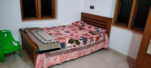 a bedroom with a bed and a green chair at Vibgyor Home away from Home in Kānnangād