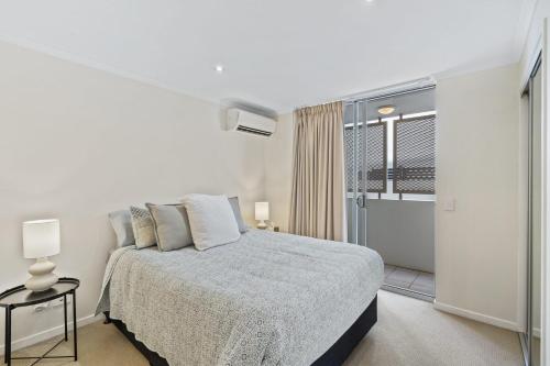 a white bedroom with a bed and a window at Modern 2BR Apt next to SouthBank Free Wifi & Pool in Brisbane