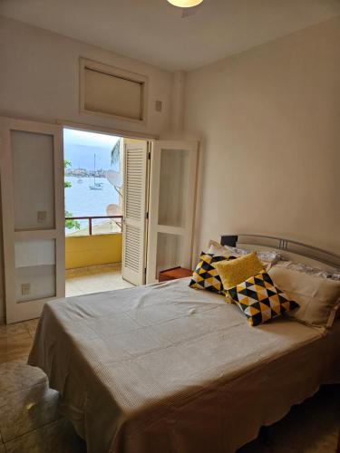 Dormitorio con cama y vistas al agua en Condomínio Cabo Frio en Cabo Frío