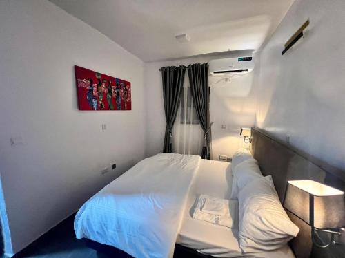 a small bedroom with a bed with white sheets at Hollywood Court Hotel in Lagos