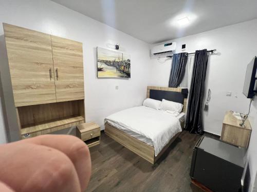 1 dormitorio pequeño con 1 cama y TV en Hollywood Court Hotel en Lagos