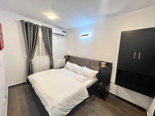 a small bedroom with a bed with white sheets at Hollywood Court Hotel in Lagos