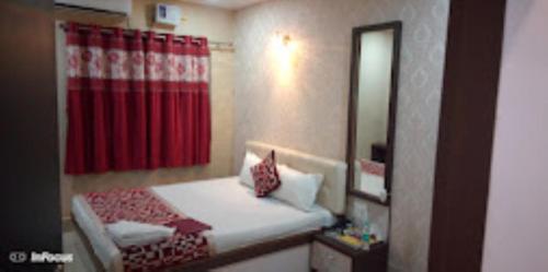 a small bedroom with a bed and a red curtain at Hotel Holiday inn , Kanakpur in Silchar