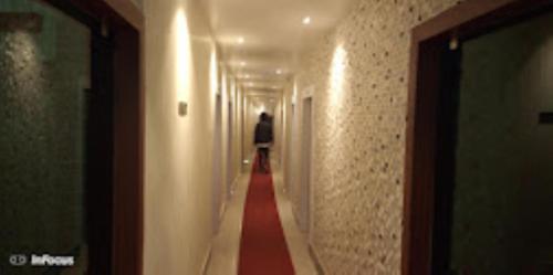 a person walking down a long hallway with a red carpet at Hotel Holiday inn , Kanakpur in Silchar