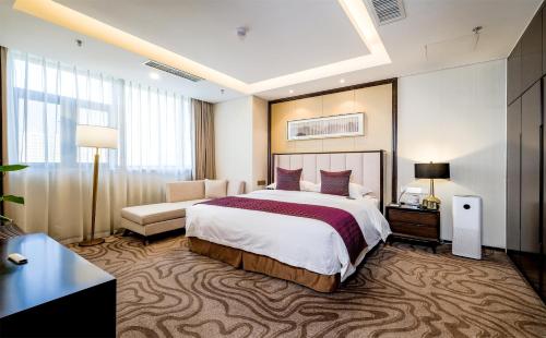 ein Hotelzimmer mit einem großen Bett und einer Couch in der Unterkunft 潍坊富华大酒店B座 The Farrington Hotel B in Weifang