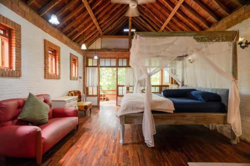 a bedroom with a canopy bed and a couch at Harum Manis Cottages in Jepara