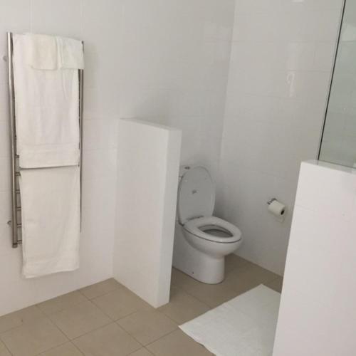 a white bathroom with a toilet and towels at Millswood Apartment in Unley
