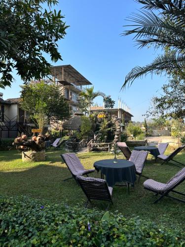 a group of chairs and a table in the grass at Hotel Riverside with Swimming pool in Sauraha