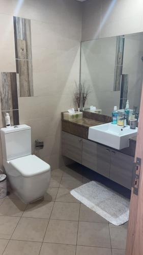 een badkamer met een wit toilet en een wastafel bij Al badaa in Dubai