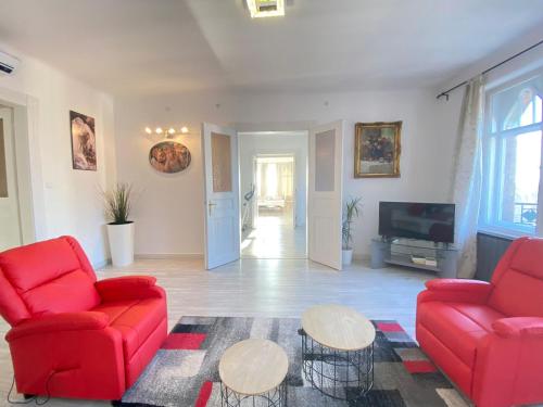 a living room with two red chairs and a tv at Penthouse in the castle in Budapest