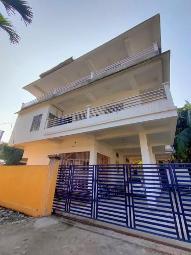 dom z niebieskim płotem przed nim w obiekcie Panchalaya Homestay w mieście Guwahati