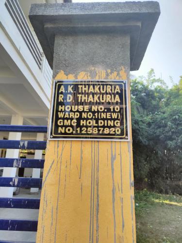 a sign on a column in front of a building at Panchalaya Homestay in Guwahati