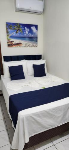 Una cama grande con almohadas azules y blancas. en Pousada Enseada São Miguel de frente para o mar, en Penha