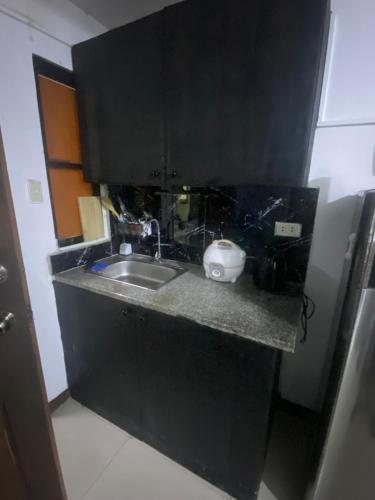 - une cuisine avec un évier et un comptoir noir dans l'établissement Fionas Apartment, à Manille
