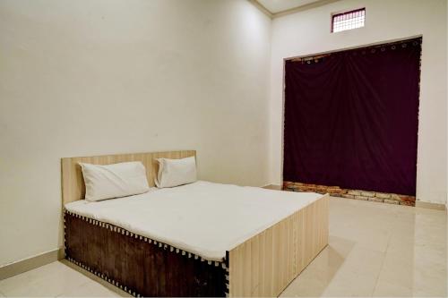 a bed in a room with a purple curtain at Spot On Chaudhary House in Hāthras