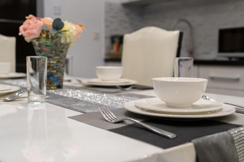 a table with plates and cups and a vase of flowers at Luks Lofts Hotel & Residences in Batangas City