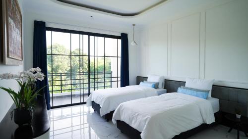 Habitación blanca con 2 camas y ventana grande. en Inori Villas, en Canggu