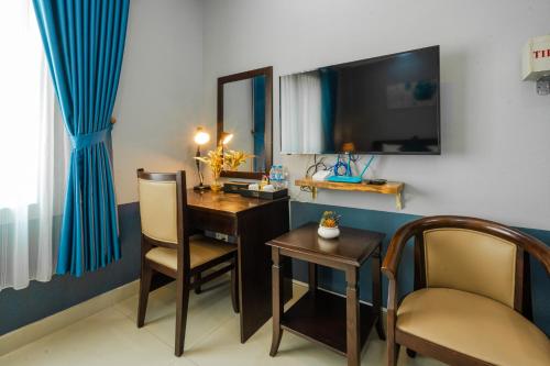 een kamer met een bureau, een televisie en een stoel bij La Serena Boutique Hotel in Ho Chi Minh-stad