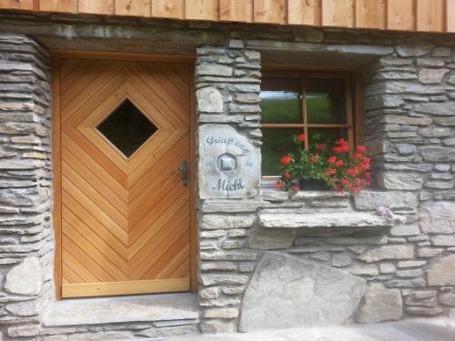 a wooden door of a stone building with flowers in a window at Miehl in Heiligenblut