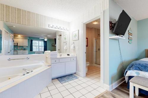 een badkamer met een bad en een wastafel en een tv bij Golf n' Sea B in Calabash