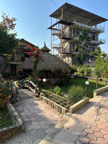 a building with a thatch roof next to a garden at Hotel Riverside with Swimming pool in Sauraha