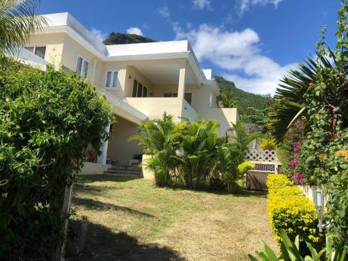 a large white house with a yard with plants at Black River Villa Turquoise 3bdr, sea view in Rivière Noire