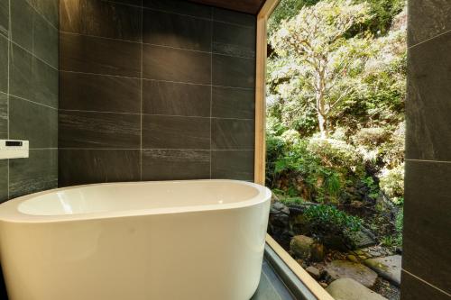 uma banheira na casa de banho com uma janela em Kinosaki Yamamotoya em Toyooka