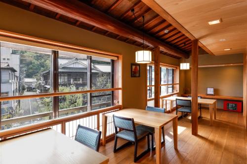 a dining room with a table and chairs and windows at Kinosaki Yamamotoya in Toyooka