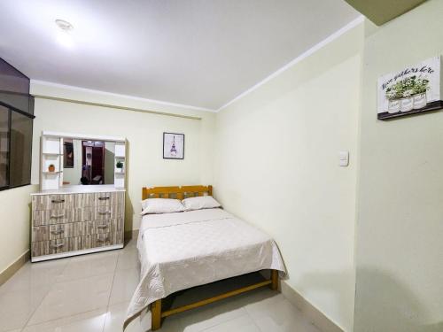 Dormitorio pequeño con cama y espejo en Karibana, en Huarmey