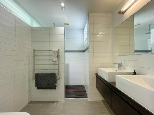 a white bathroom with a sink and a mirror at Luxury Beachside Retreat in Papamoa