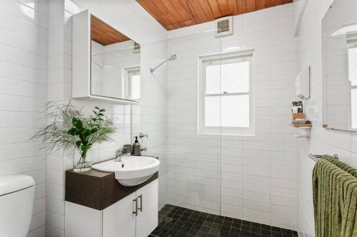 a white bathroom with a sink and a toilet at Vintage 2BR CBD Apartment w/River View in Perth
