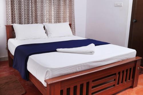 Una cama con sábanas blancas y almohadas. en Bellfields Homestay, en Meenangadi