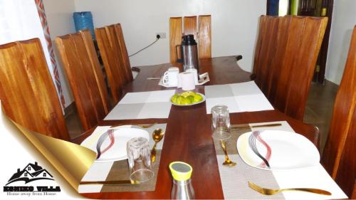 a dining room table with two white plates at Esniko Villa in Narok
