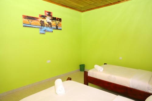 two beds in a room with green walls at Esniko Villa in Narok