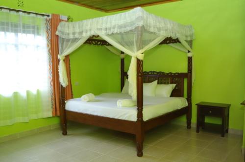 a bedroom with a canopy bed in a green room at Esniko Villa in Narok