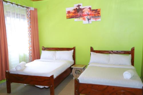 two beds in a room with green walls at Esniko Villa in Narok