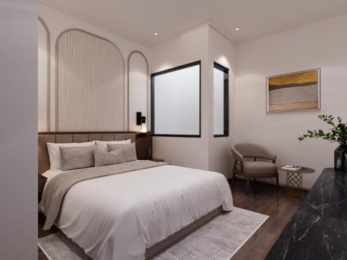 a bedroom with a large white bed and a chair at L'amant de Hanoi Hotel - khách sạn Lamant de Hà Nội in Hanoi